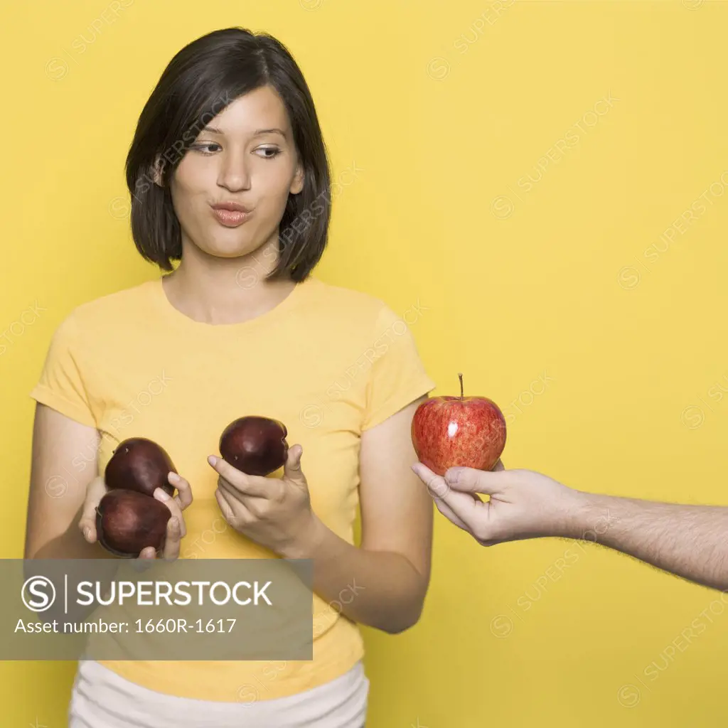 Young woman looking at a human hand giving an apple