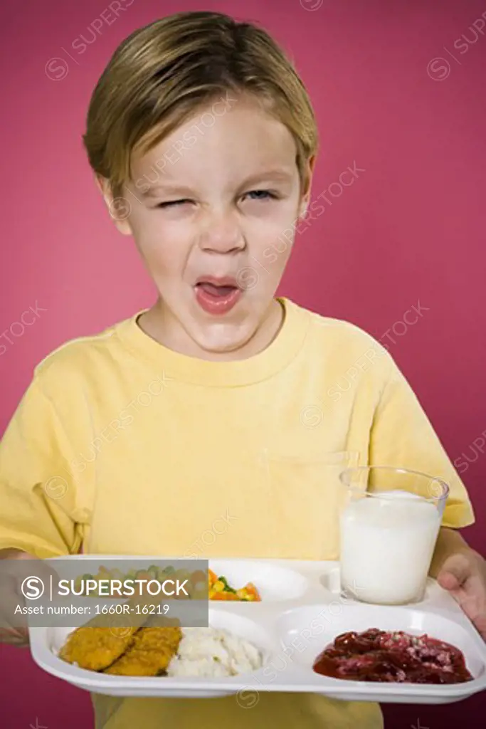Boy making funny face with tray of food