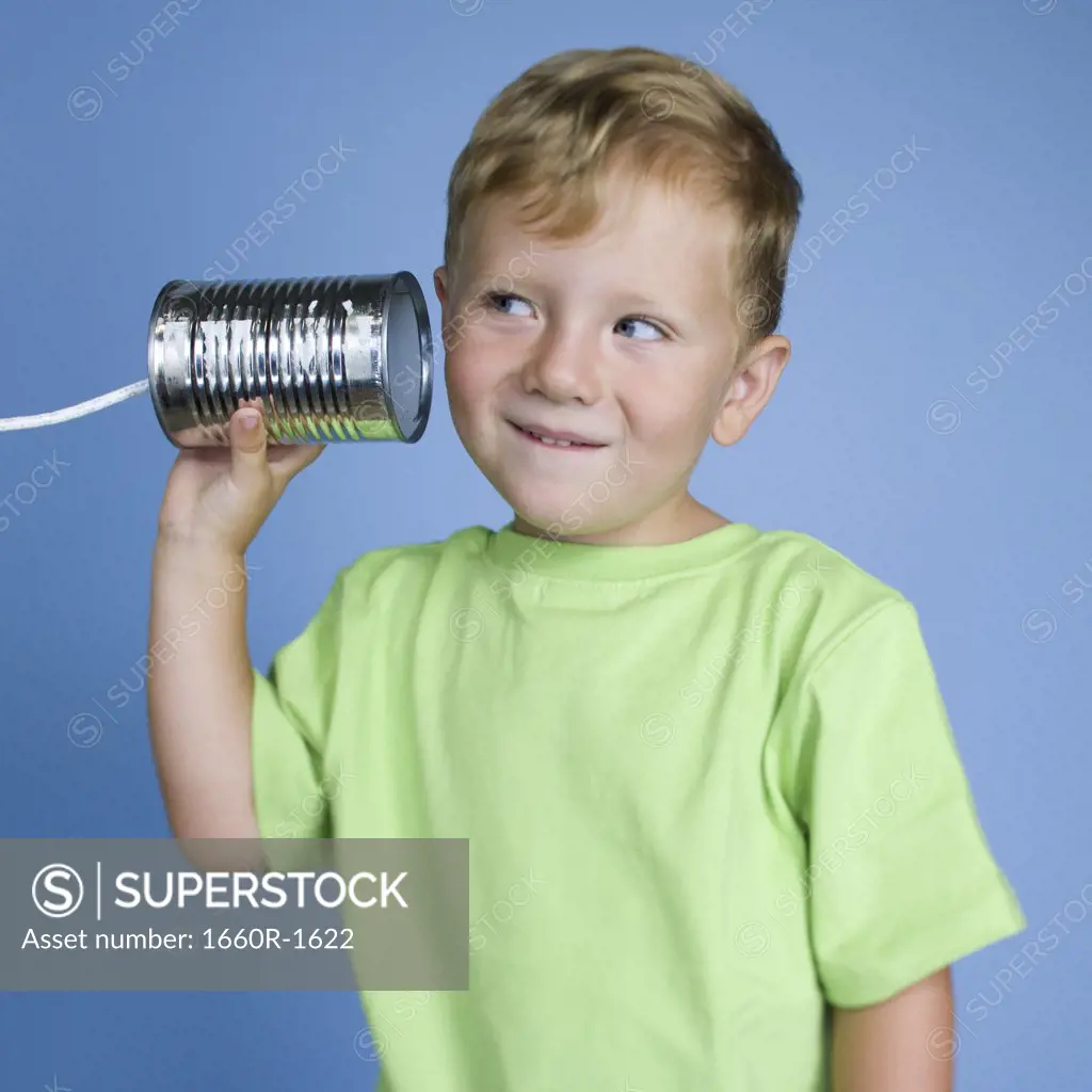 Close-up of a boy holding a tin can phone to his ear