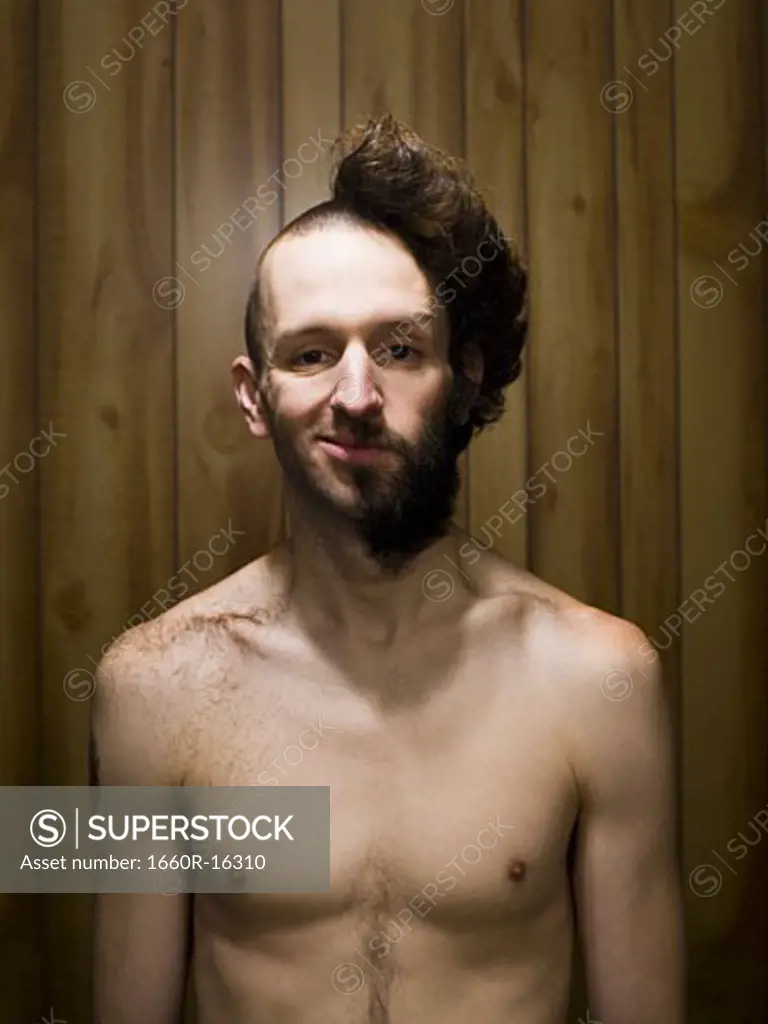 Man with half shaved head and beard half smiling