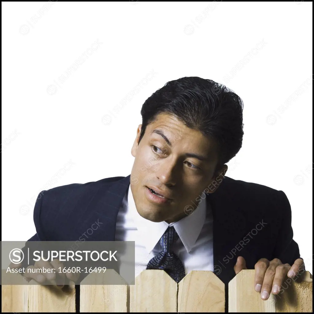 Businessman looking over wooden fence