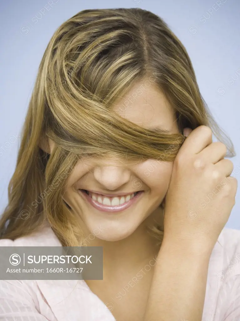 Closeup of smiling woman hiding eyes with hair