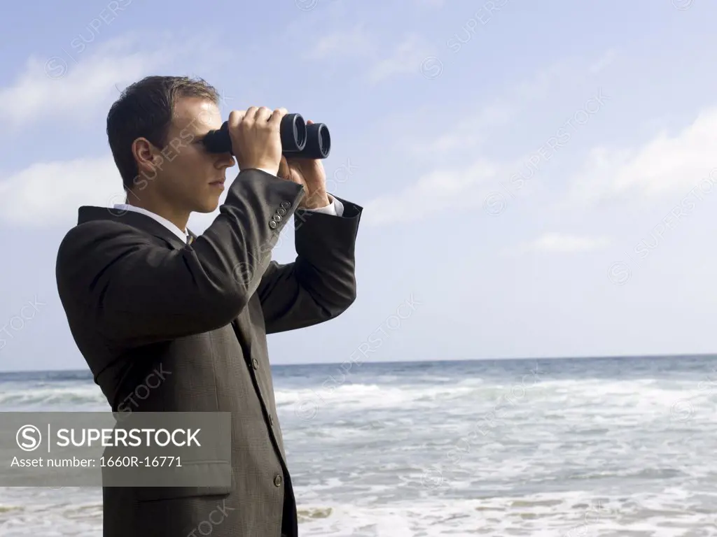 Businessman looking through binoculars outdoors