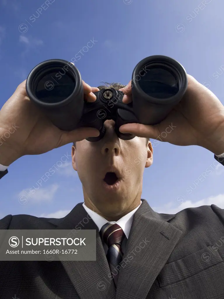 Businessman looking through binoculars outdoors