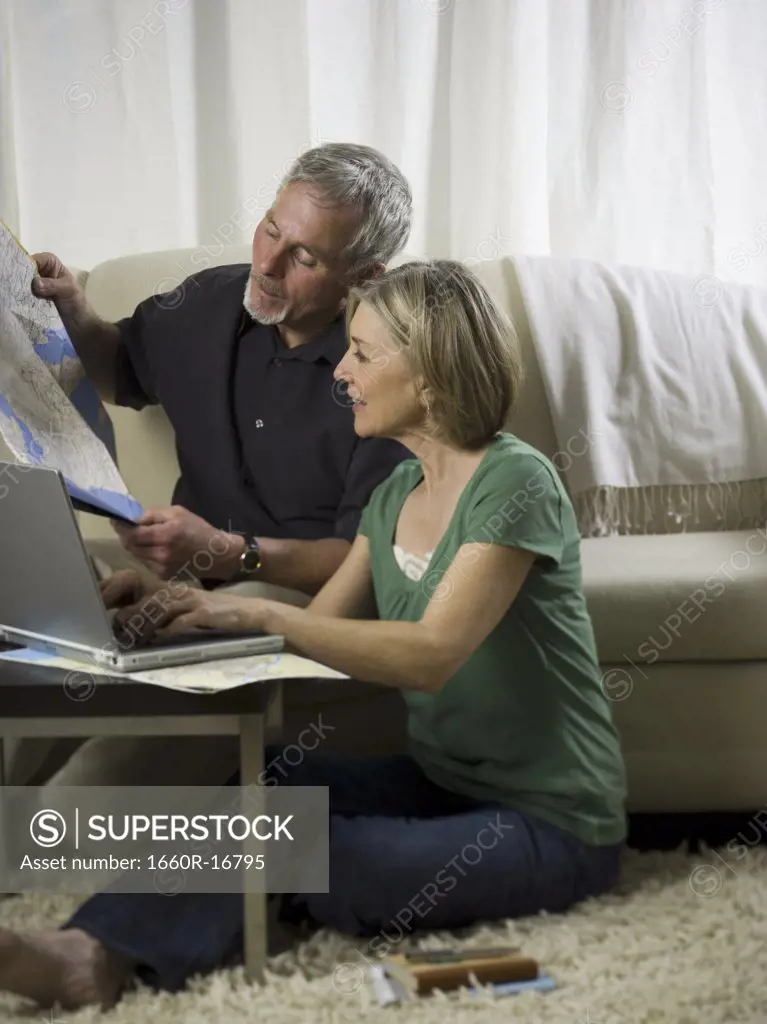 Elderly couple sitting in front of a laptop and looking at a map
