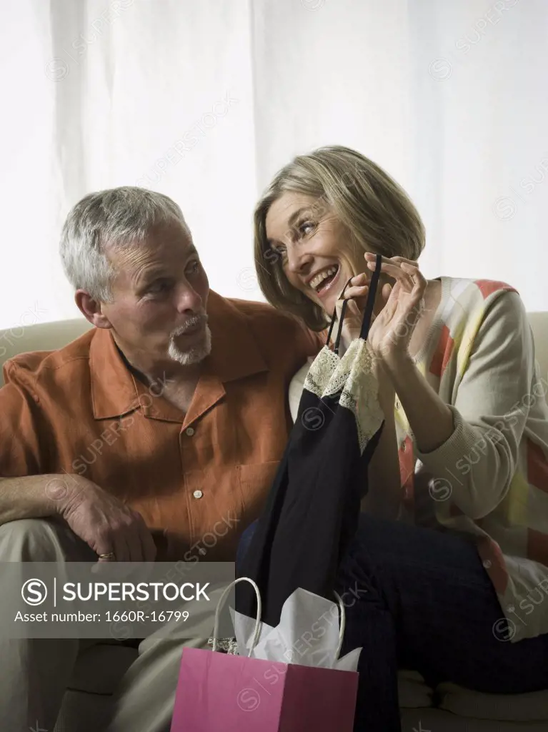 Senior woman holding a dress and looking at a senior man
