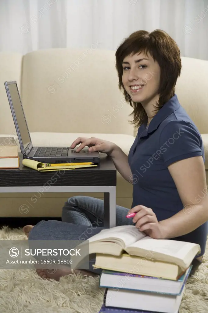 Portrait of a teenage girl using a laptop and smiling