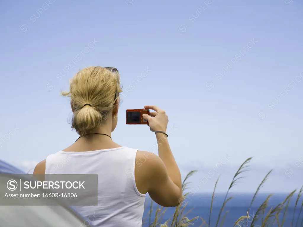 Rear view of a young woman taking a photograph with a digital camera