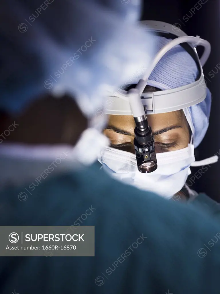 Female doctor in scrubs with head light in surgery