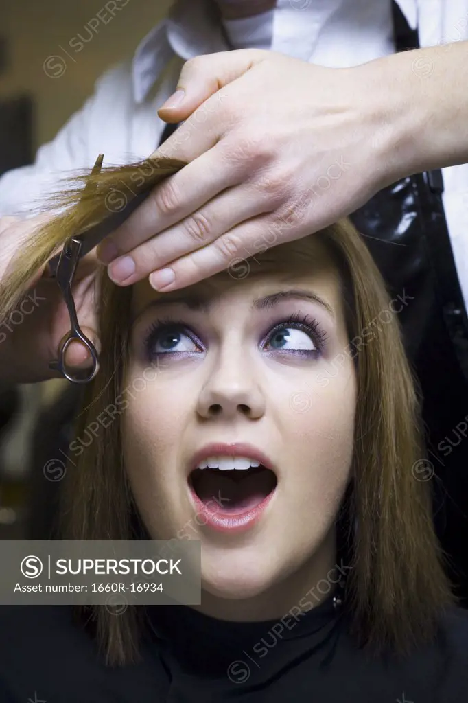 Hairdresser cutting young woman's hair