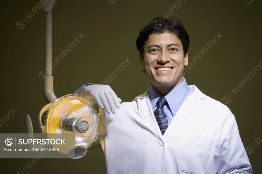 Male doctor or dentist with surgical lamp smiling