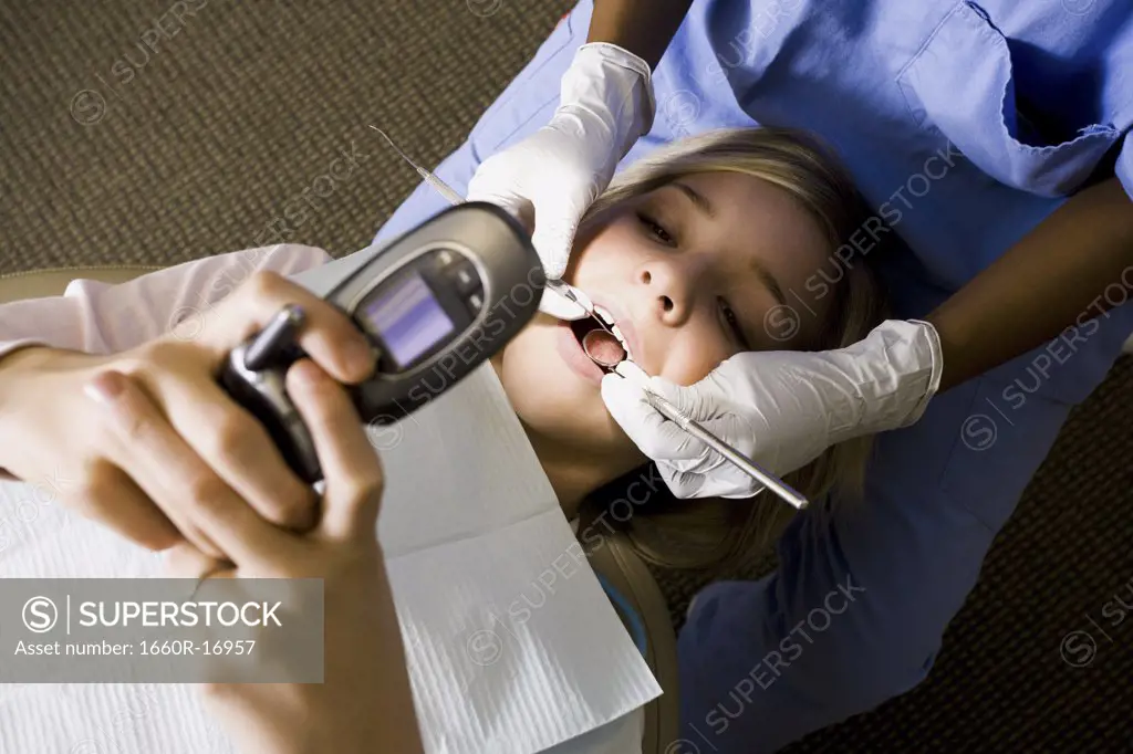 Girl having dental exam holding cell phone