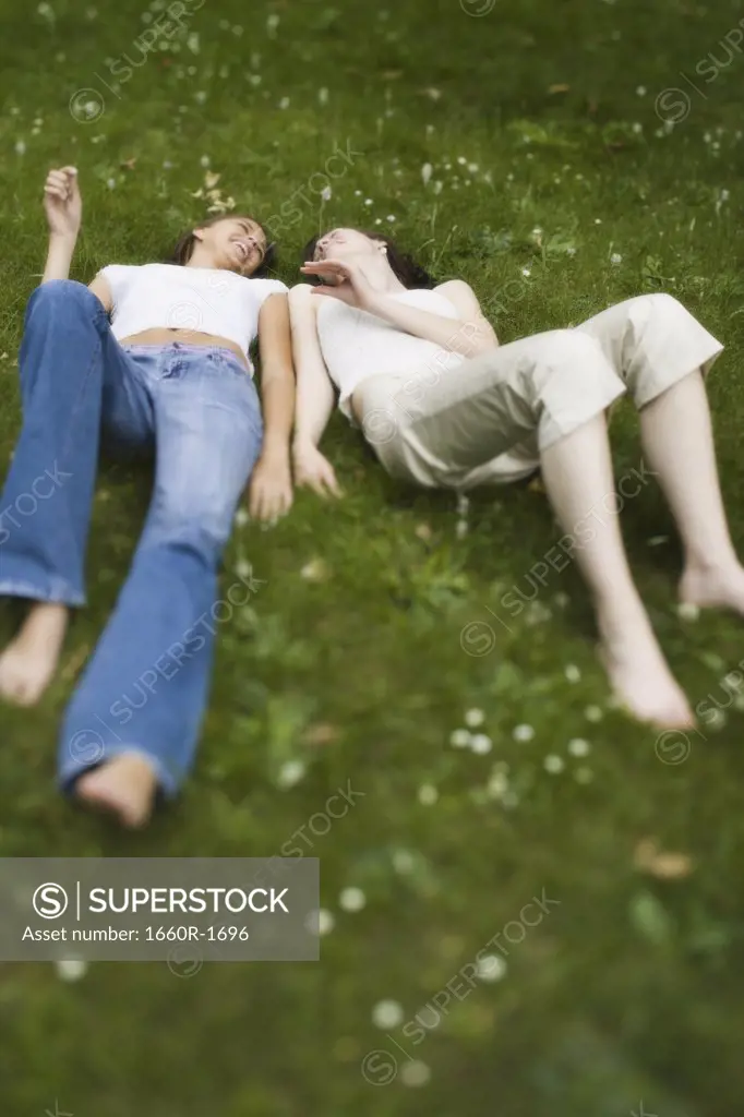 High angle view of two teenage girls lying on grass