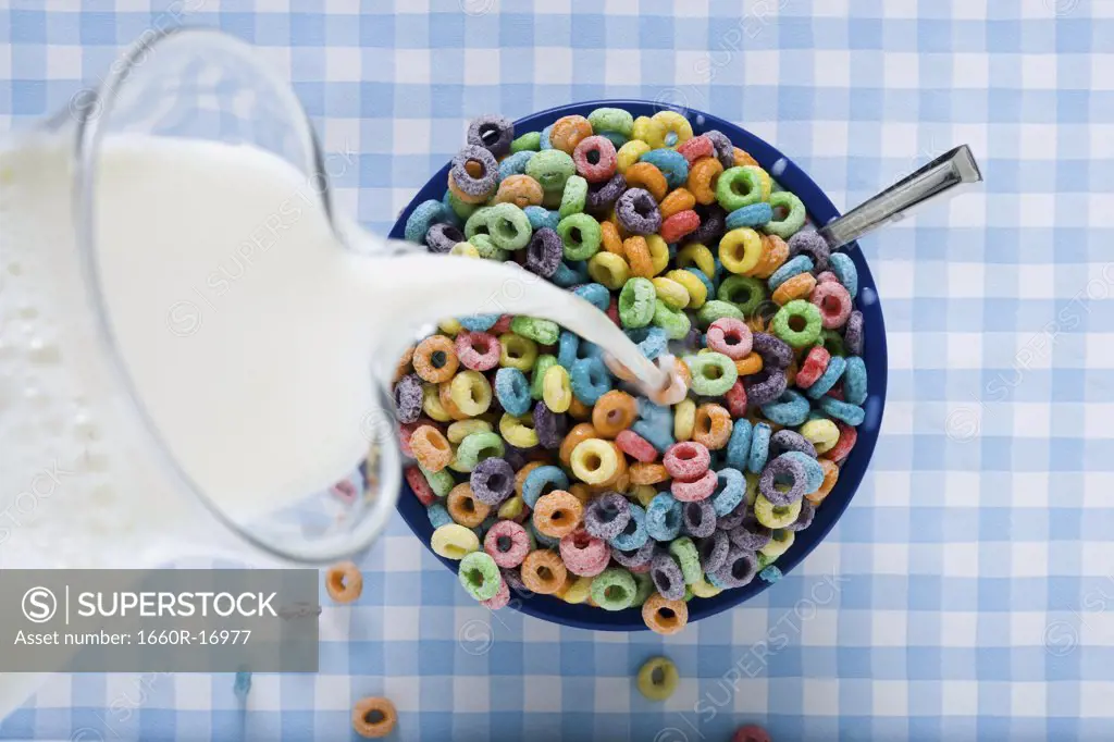 Milk pouring from jug into cereal bowl