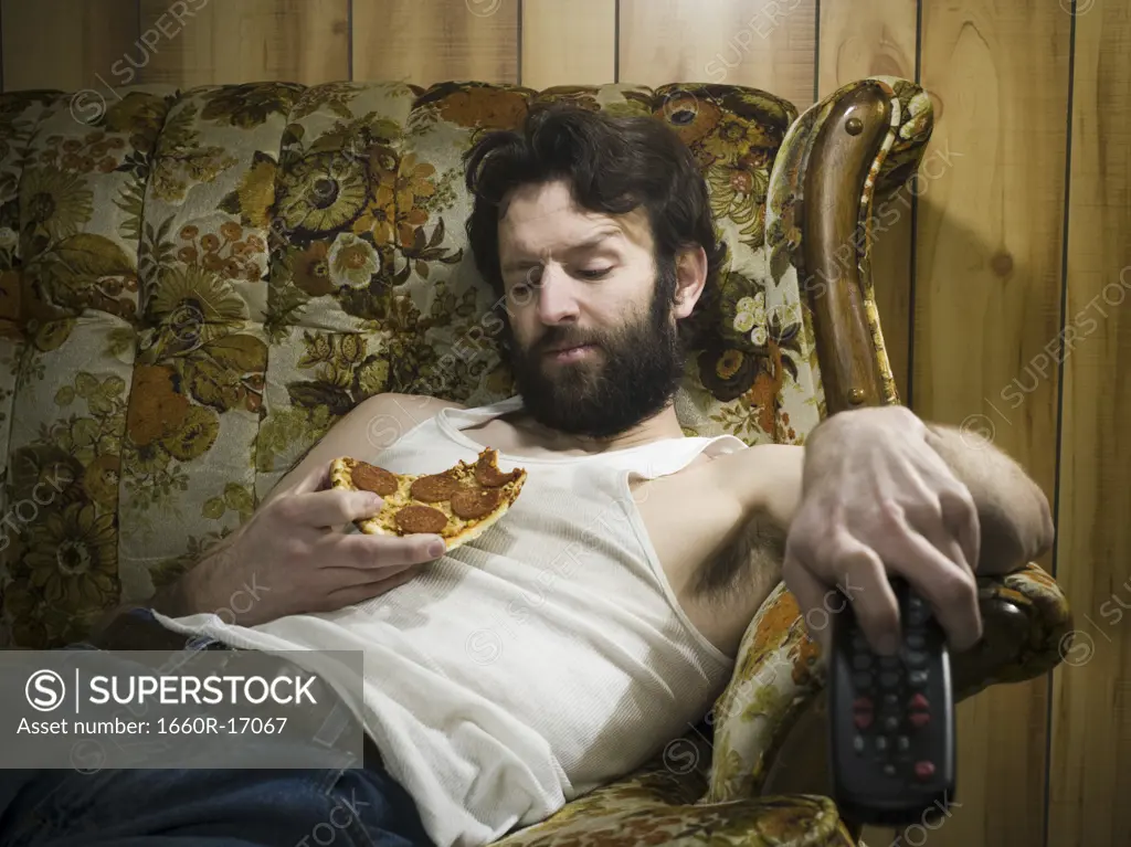 Man on sofa with pizza and remote