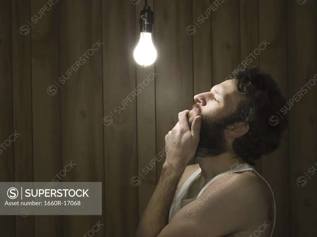 Man looking thoughtfully at light bulb