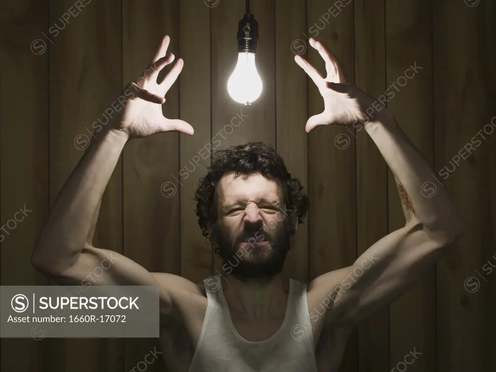 Man reaching to light bulb gritting teeth