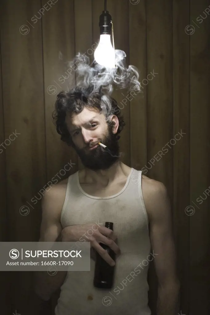Man standing under light bulb with cigarette and beer bottle