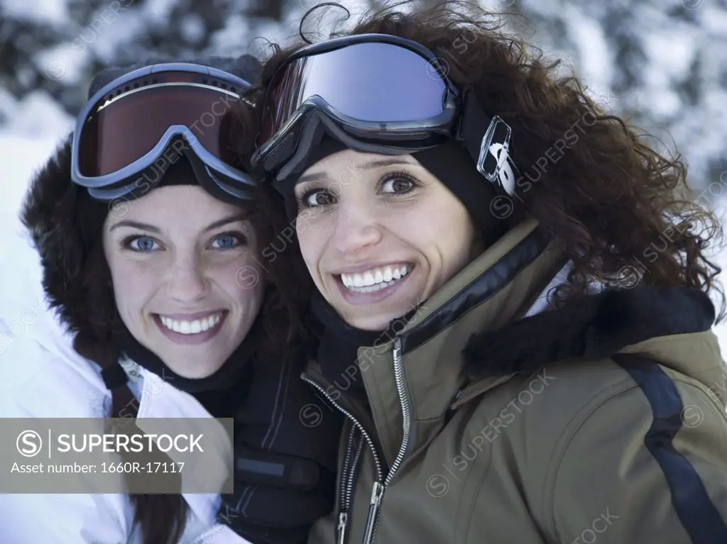 Two women outdoors in winter with ski goggles smiling