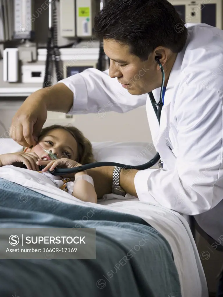 Doctor examining young girl in hospital with stethoscope