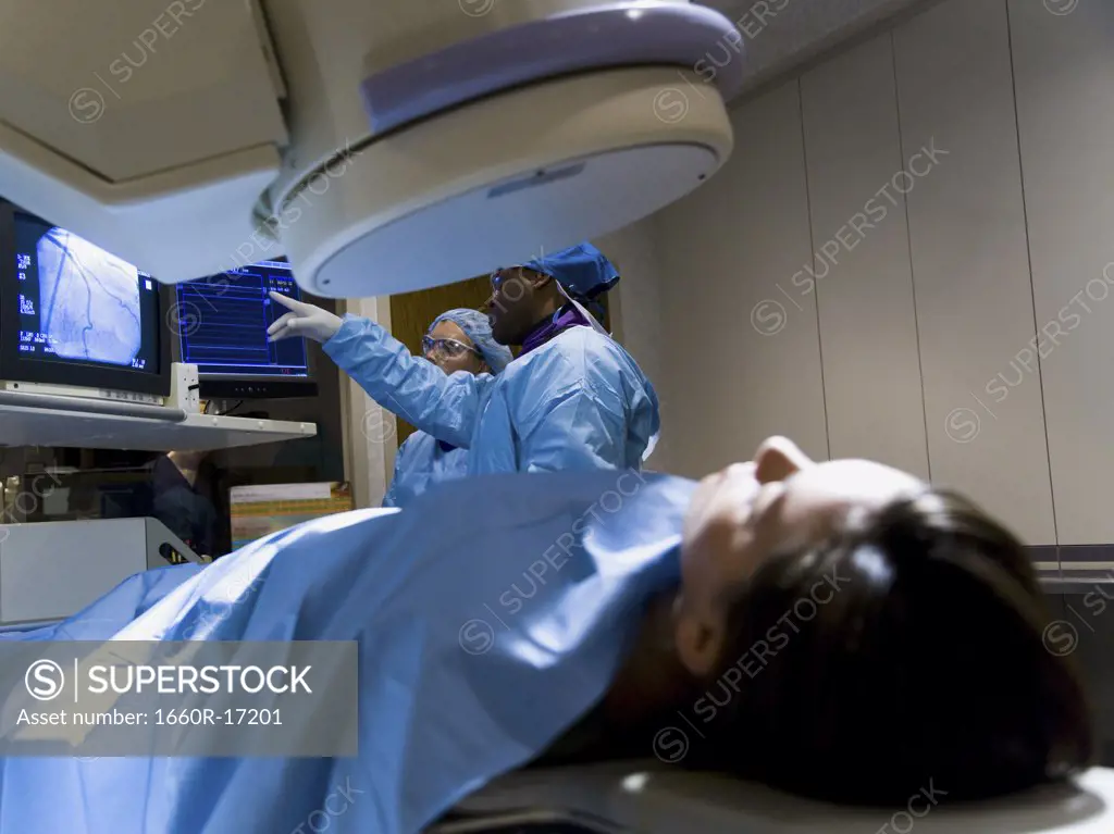 Woman on diagnostic bed with male and female technicians looking at monitors