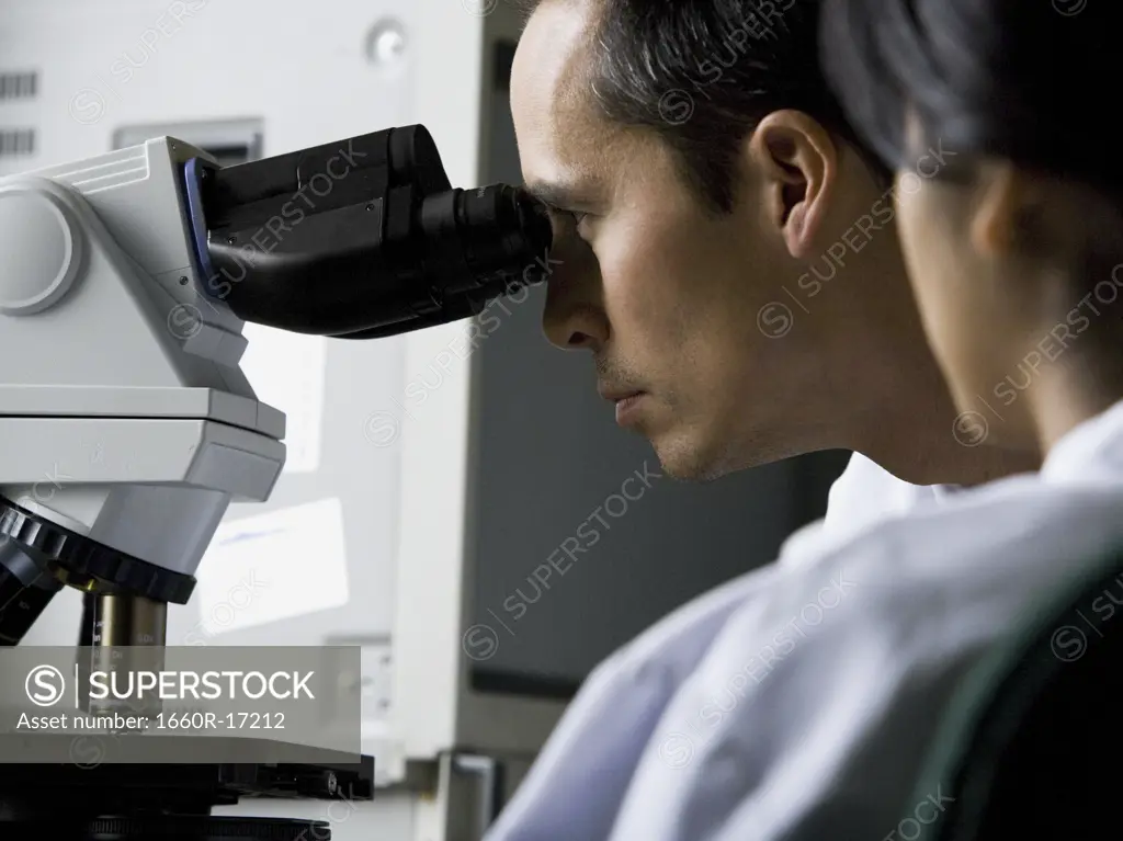 Male laboratory technician looking in microscope