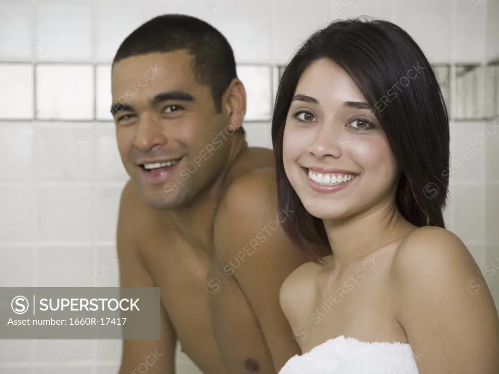 Man and woman in steam bath with towels smiling