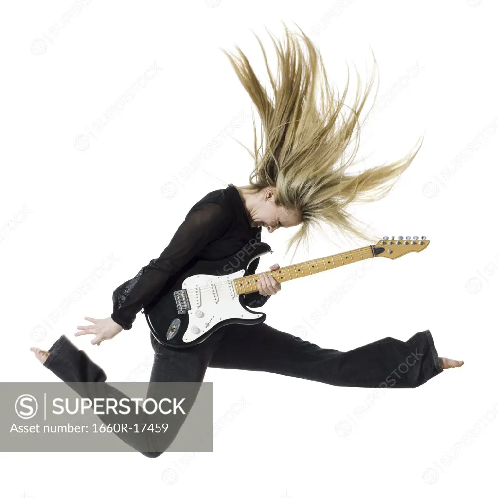 Profile of woman jumping with electric guitar