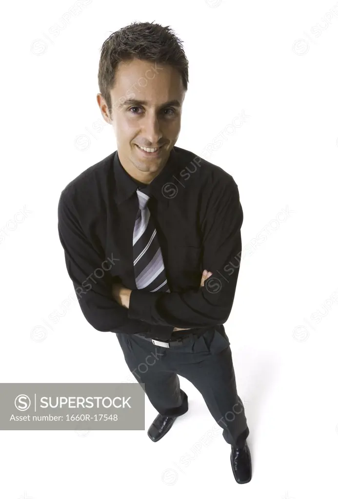 Man in business attire standing with arms crossed smiling