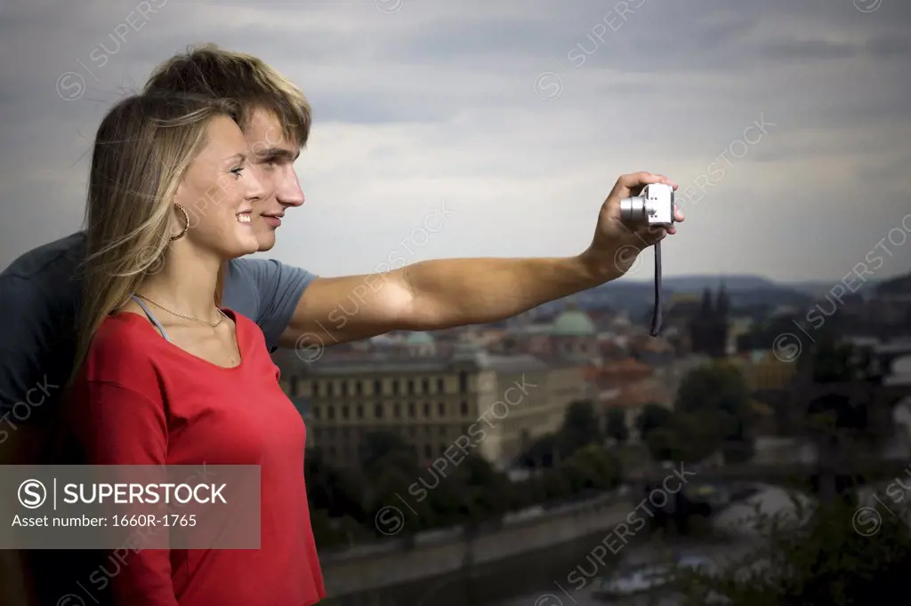 Profile of a young man and a young woman taking a photograph of themselves