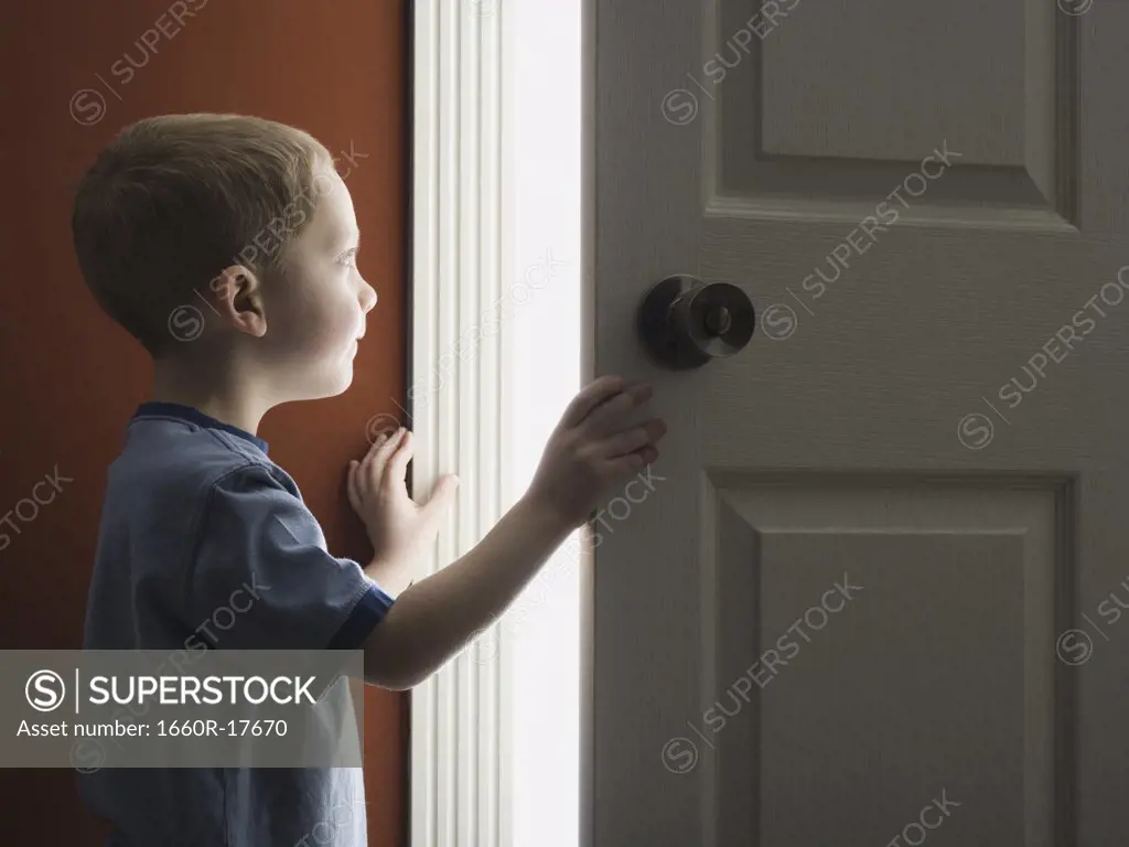 Young boy looking through doorway