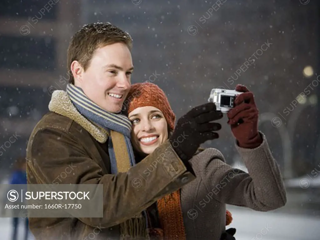 Man and woman taking a photo outdoors in winter