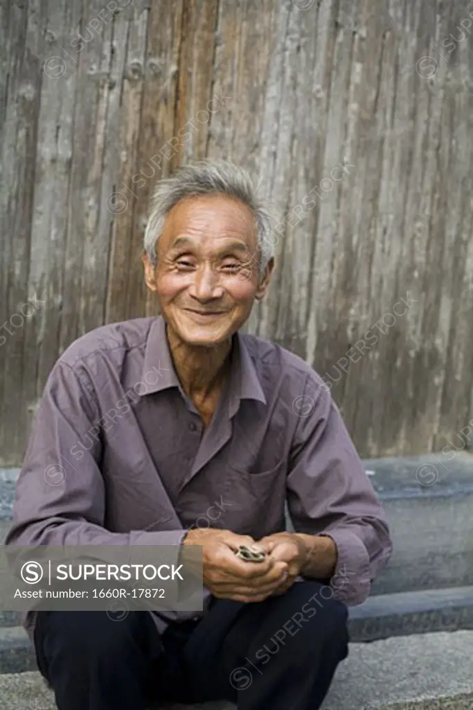 Old man sitting outdoors smiling