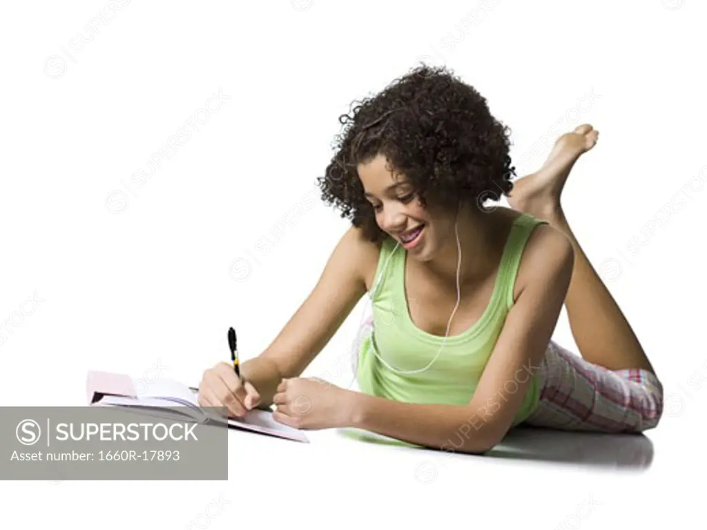 Teenage girl with braces and earbuds writing and smiling