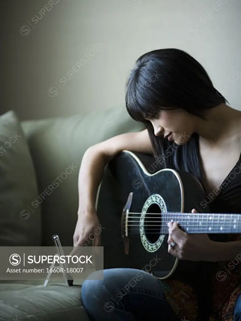 Woman tuning guitar with metronome