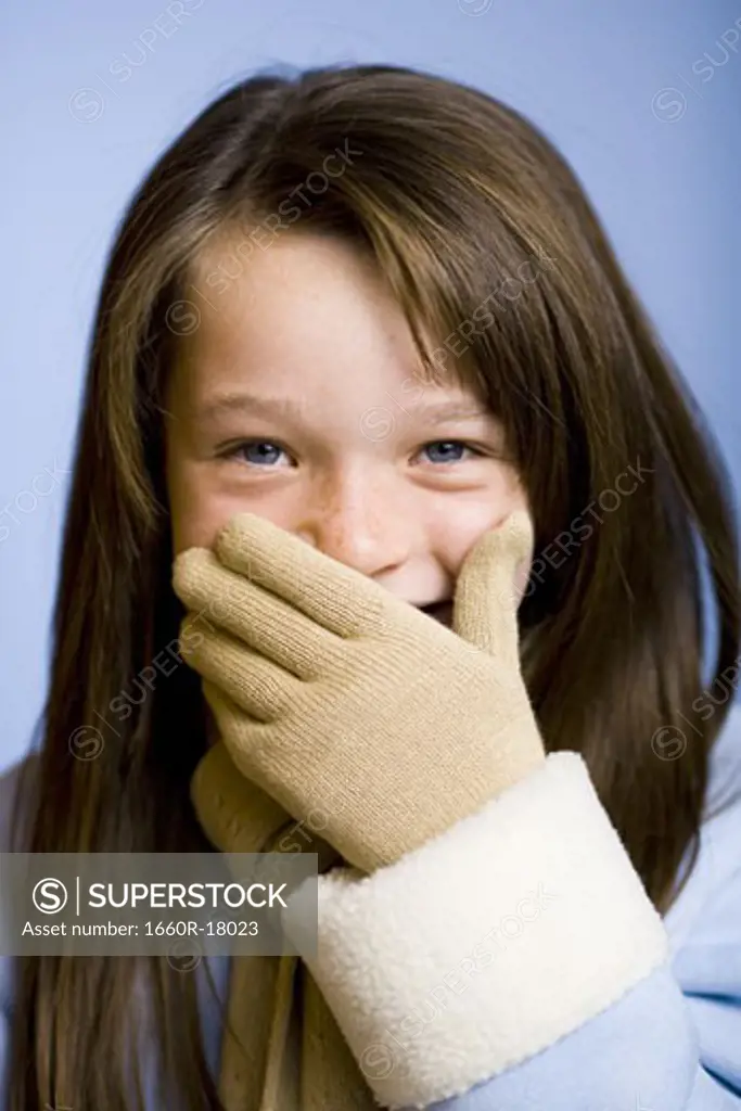 Girl with mittens covering mouth and smiling