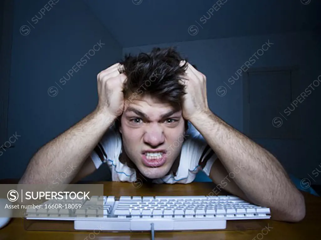 Man at keyboard with hands on head snarling