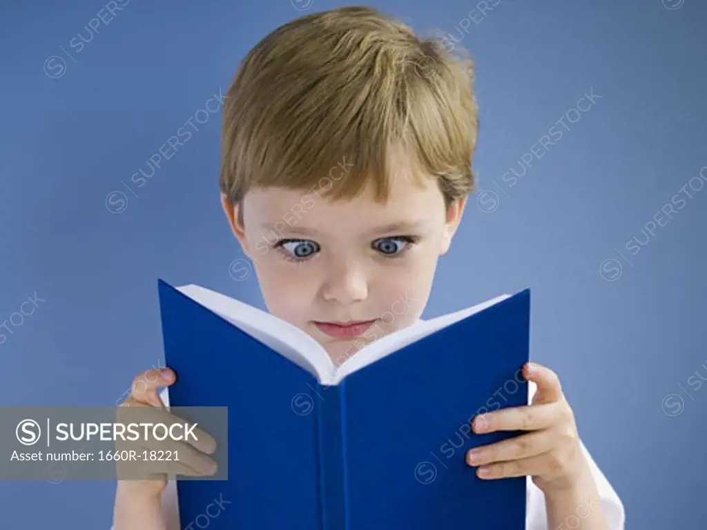 Boy reading harcover book cross eyed