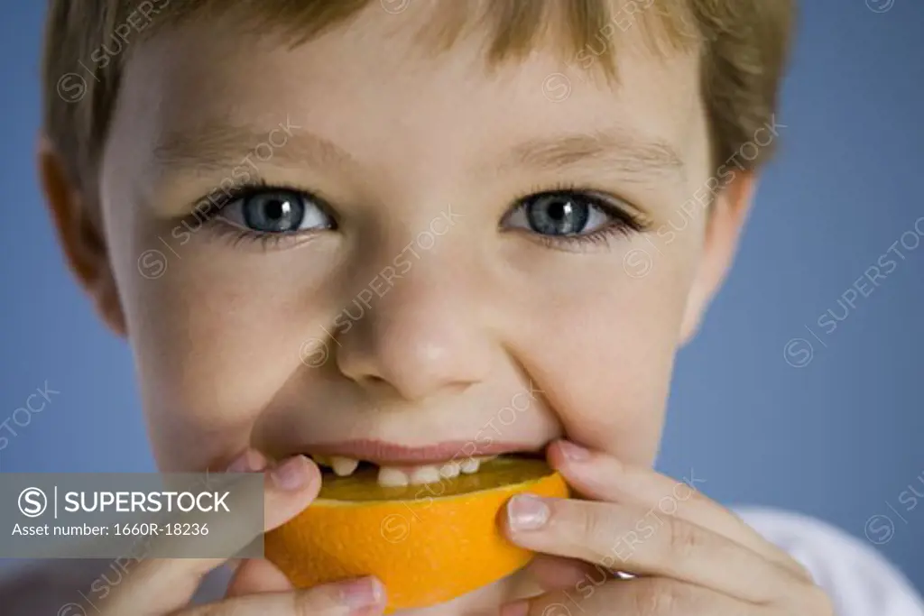 Closeup of boy eating orange wedge