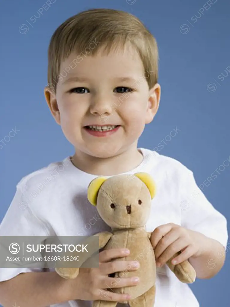 Boy holding teddy bear smiling