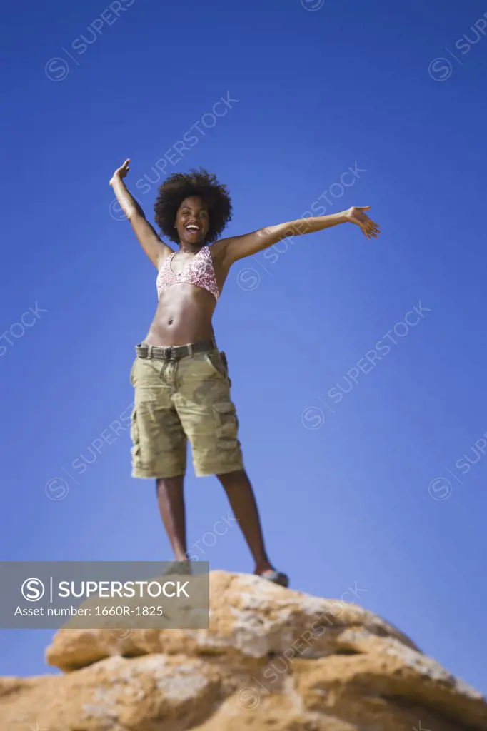 Low angle view of a young woman standing on a rock