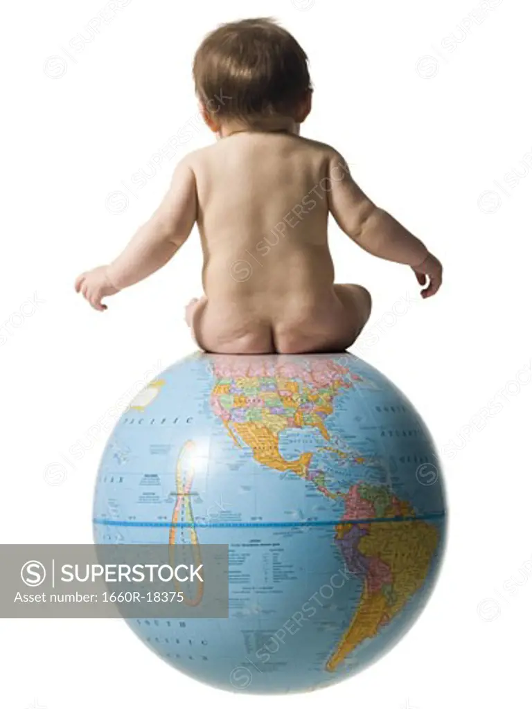 Rear view of naked baby sitting on globe