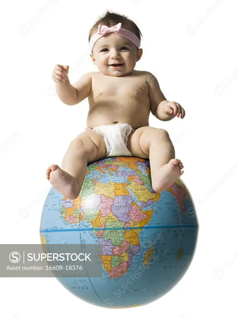 Baby girl in diaper smiling and sitting on globe