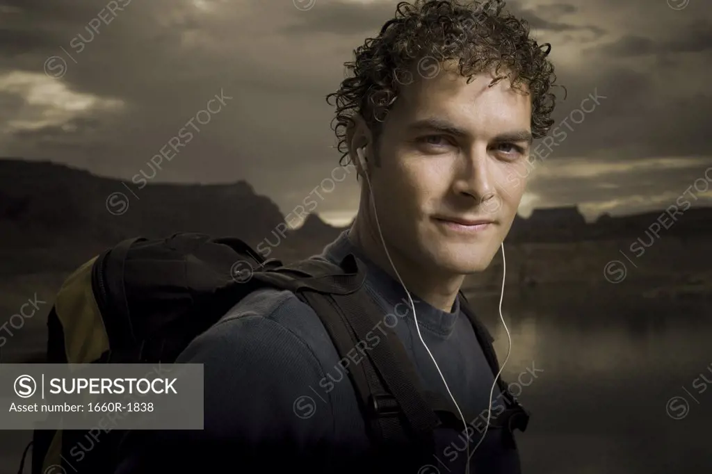 Portrait of a young man wearing headphones and carrying a backpack
