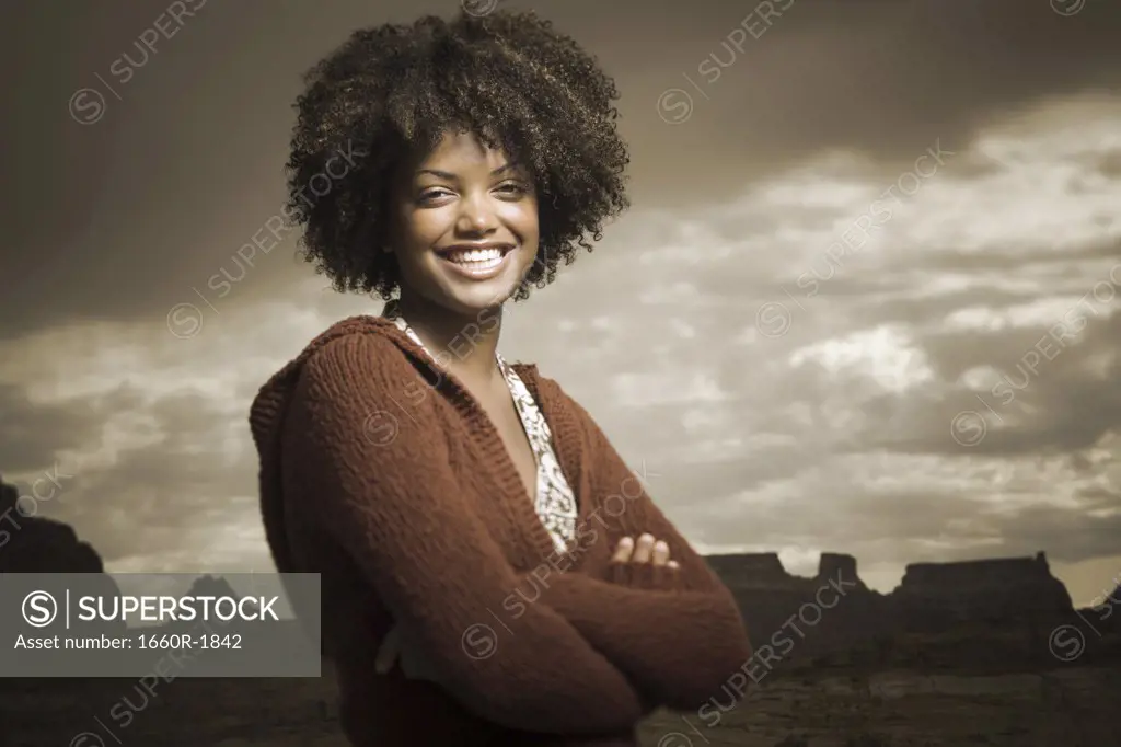 Portrait of a young woman standing with her arms crossed
