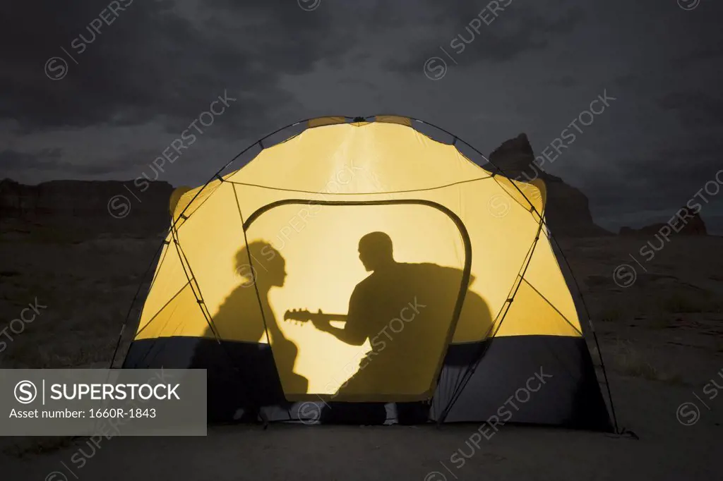 Silhouette of a couple sitting inside a tent