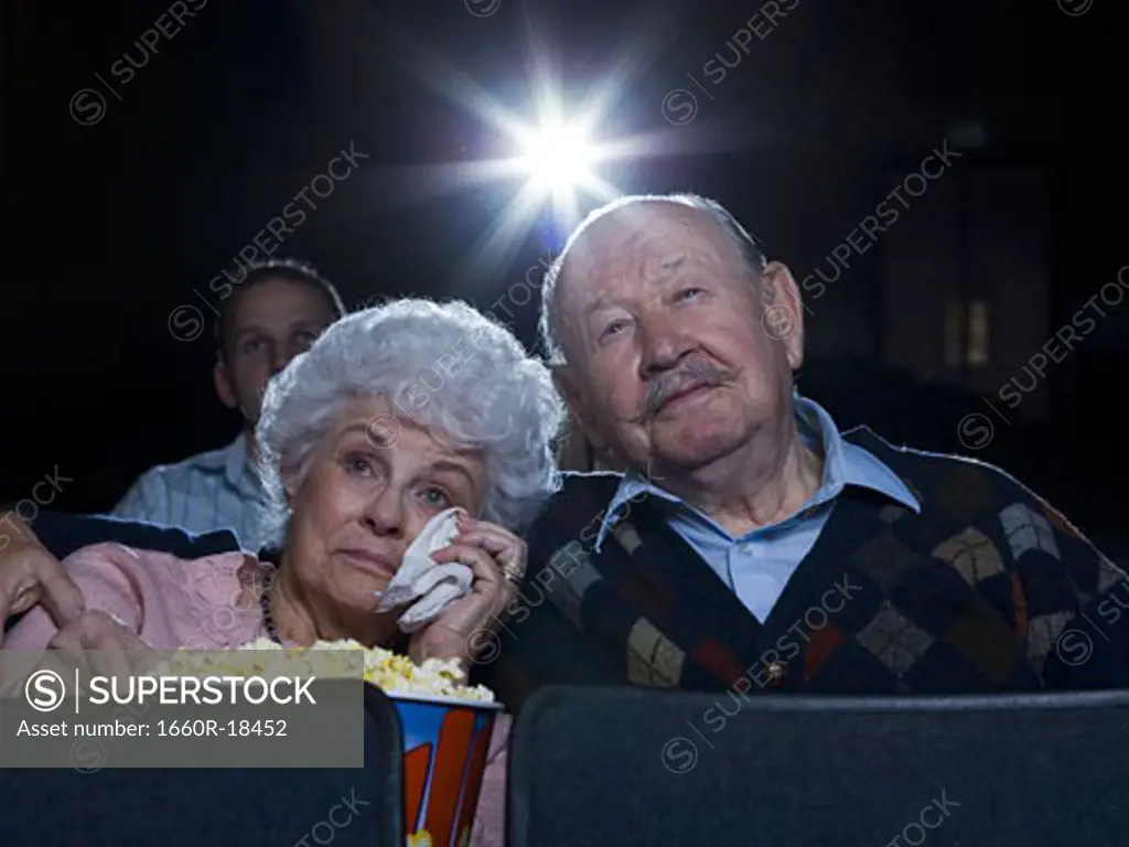Man and woman watching movie in theater crying with popcorn