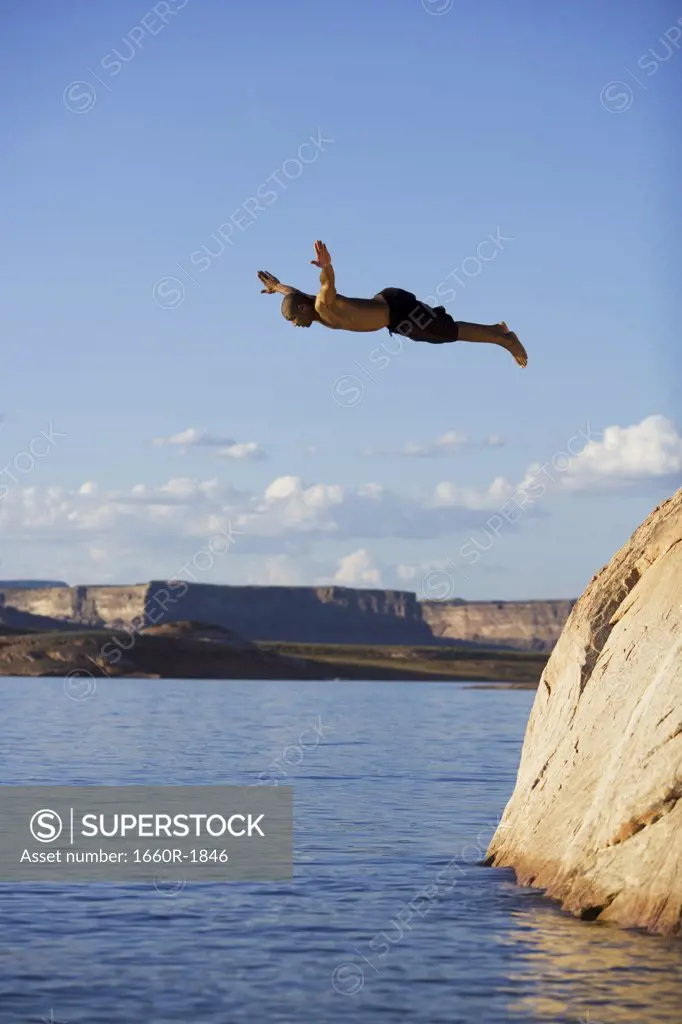 Young man diving off a rock into a lake