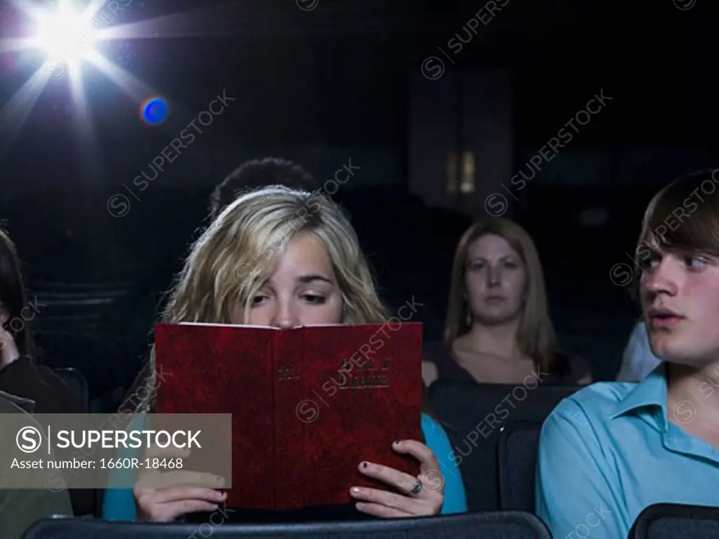 Girl reading hardcover book at movie theater