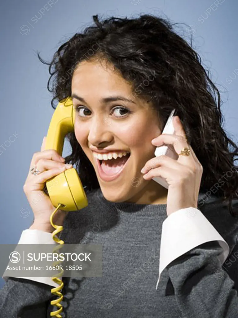 Woman talking on cell phone and retro telephone smiling